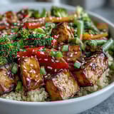Fluffy quinoa and crispy tofu are tossed with vibrant broccoli and bell peppers, all coated in a glossy teriyaki sauce.