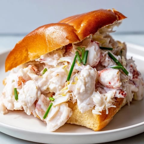 A Connecticut-style New England Lobster Roll featuring warm, buttery lobster piled into a lightly toasted split-top bun.