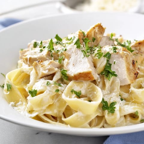 Creamy Fettuccine Alfredo twirled on a fork, ready to serve with a glass of white wine.