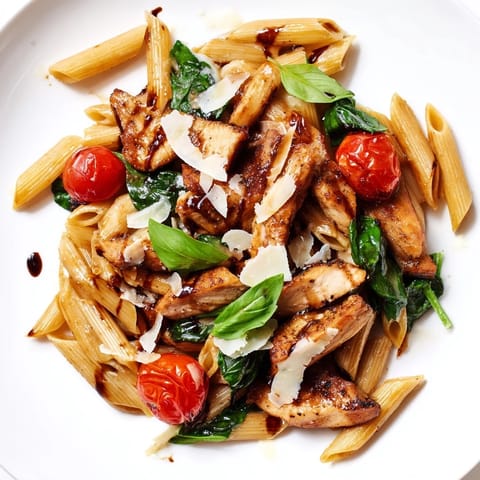 A close-up of Balsamic Glazed Chicken Pasta twirled on a fork, showing tender chicken pieces and glistening sauce.