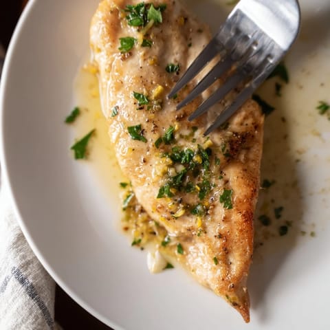 Freshly seared Lemon Pepper Chicken with a bright lemon-pepper crust, garnished with chopped parsley on a rustic wooden serving platter.