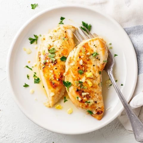 Golden-brown Lemon Pepper Chicken breasts sizzling in a skillet, glistening with a vibrant butter and lemon sauce, ready to serve.