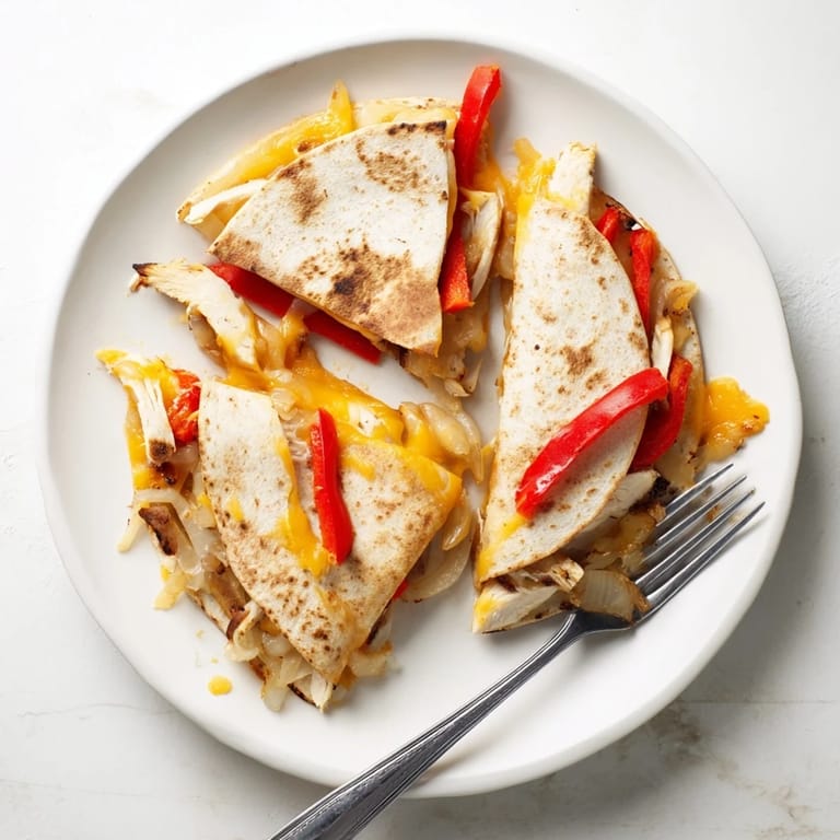 Crispy Chicken Quesadilla cooking in a skillet, featuring seasoned chicken, onions, and melted cheddar inside a golden tortilla.