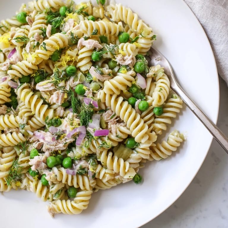 Serving suggestion for Lemony Tuna Pasta Salad: a refreshing bowl garnished with chopped parsley, red onion, and a drizzle of extra-virgin olive oil.  