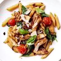A close-up of Balsamic Glazed Chicken Pasta twirled on a fork, showing tender chicken pieces and glistening sauce.