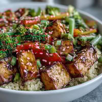 Fluffy quinoa and crispy tofu are tossed with vibrant broccoli and bell peppers, all coated in a glossy teriyaki sauce.