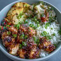 Teriyaki Chicken and Rice Bowl with glazed chicken, fluffy rice, and stir-fried vegetables on a white plate.