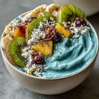 Vibrantly blue spirulina smoothie bowl, topped with juicy tropical fruits in a refreshing breakfast.